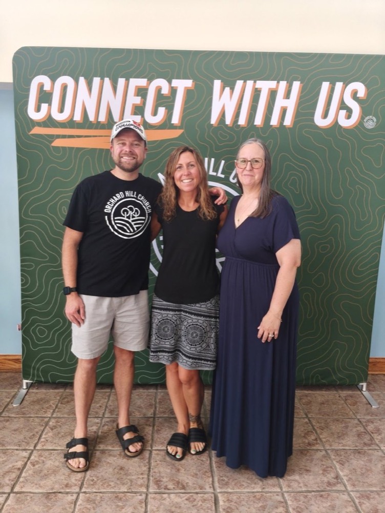 Stephanie with guests in front of a Connect With Us backdrop